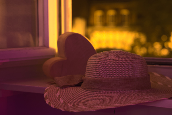 straw hat and wooden heart in front of an open window
