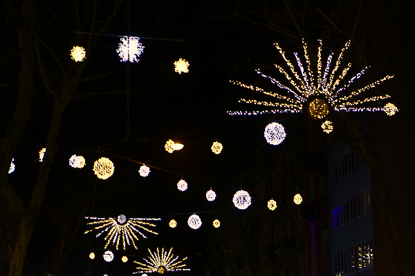 balls and stars made from many small lights hanging over the street