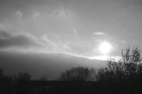 mountains and trees with sun shining on clouds