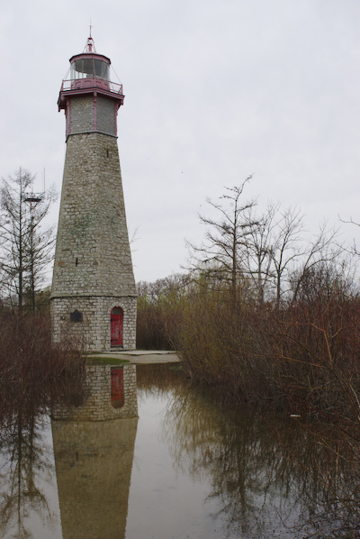 lighthouse with reflection in a water puddle