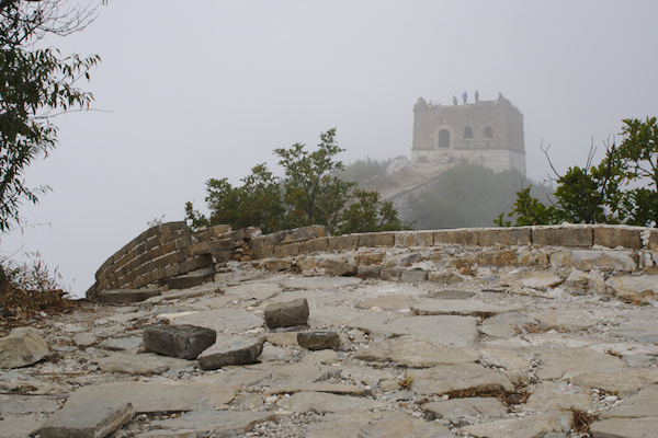 rugged Great Wall in the foreground with a tower in the fogg in the background