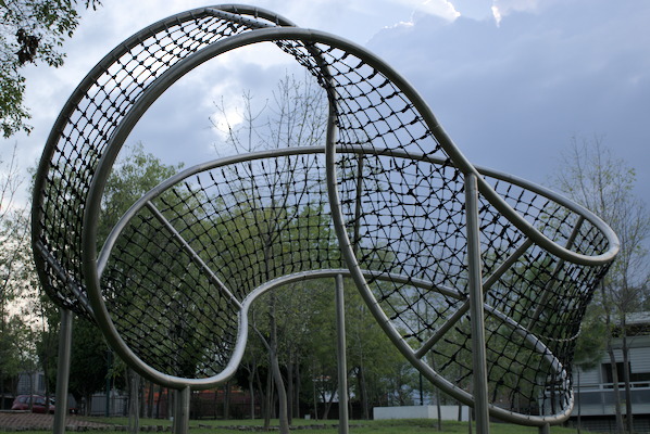 climbing net that in the shape of a Moebius strip with pillars on grass