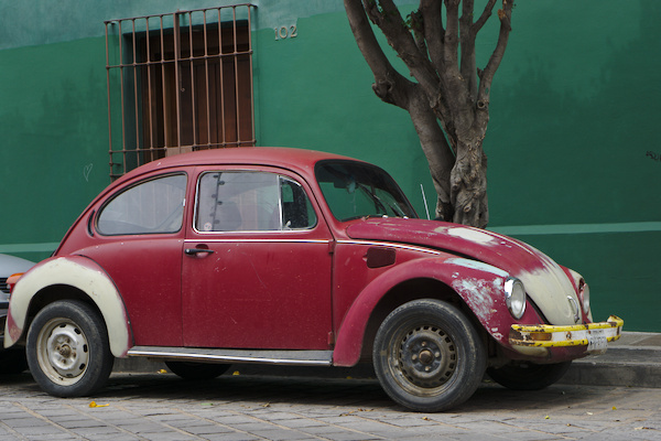 old red VW beetle in front of a green wall