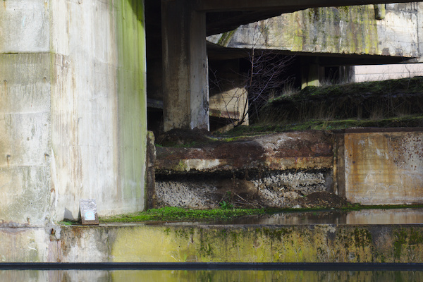 lower walls of a former blast furnace with moss and reflections in a water surface