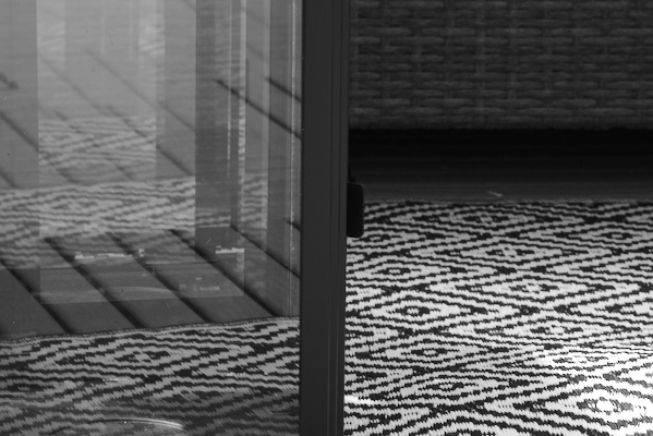 details of a carpet and balcony furniture with reflections in a glass lantern