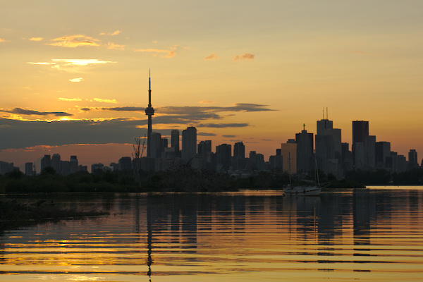 skyline of Toronto with reflection in Lake Ontario during sunset