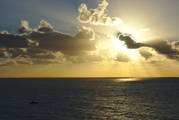 sun behind the clouds over the sea