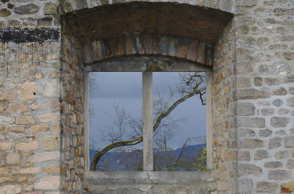 stone wall with window looking out to a tree
